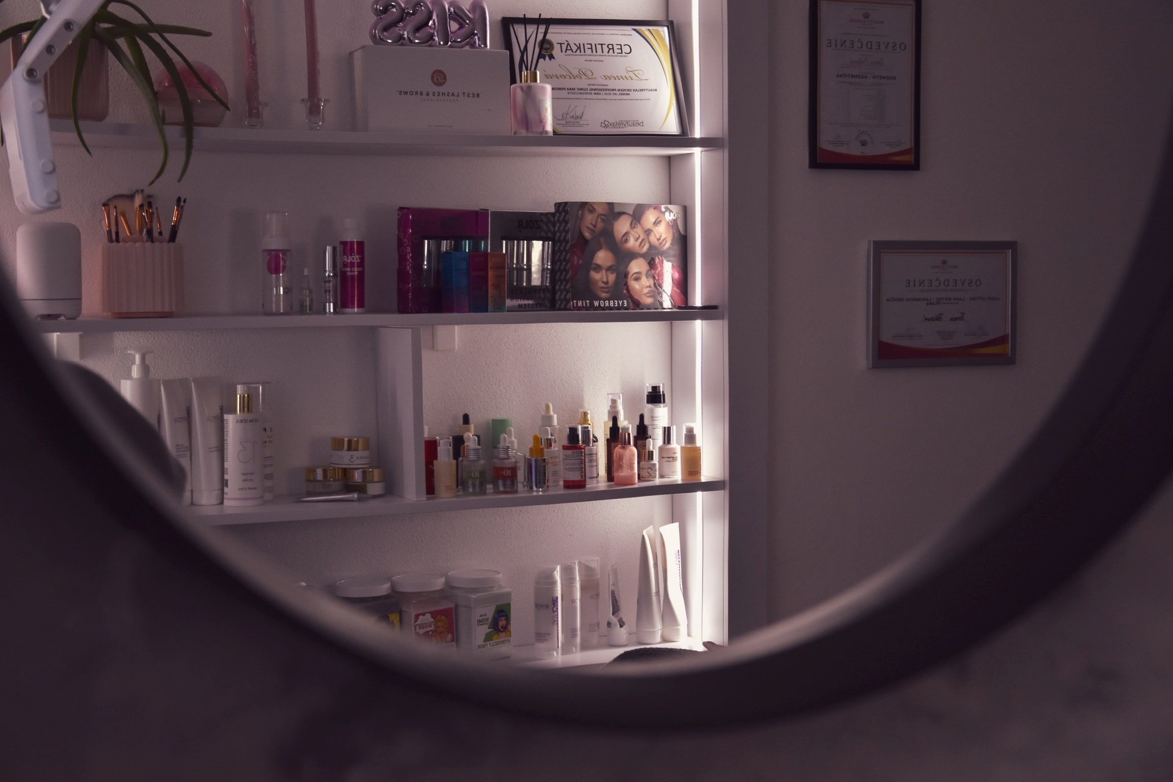 Okrúhle zrkadlo a police s produktmi v salóne Timea Skincare